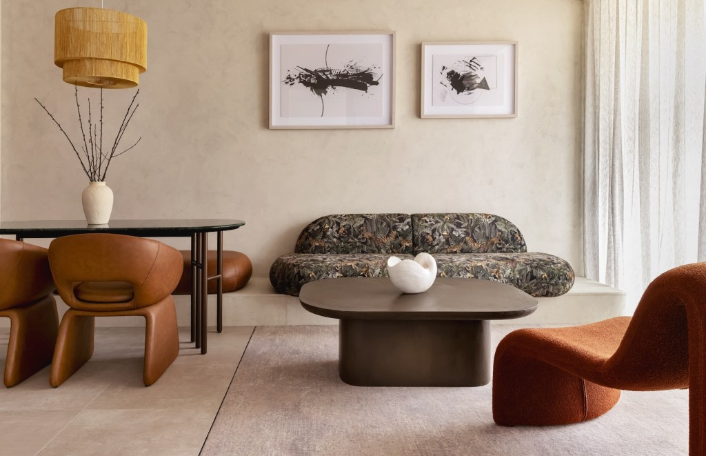 Patterned sofa, leather modern chair, oval dining table with twigs on top, and leather dining chairs