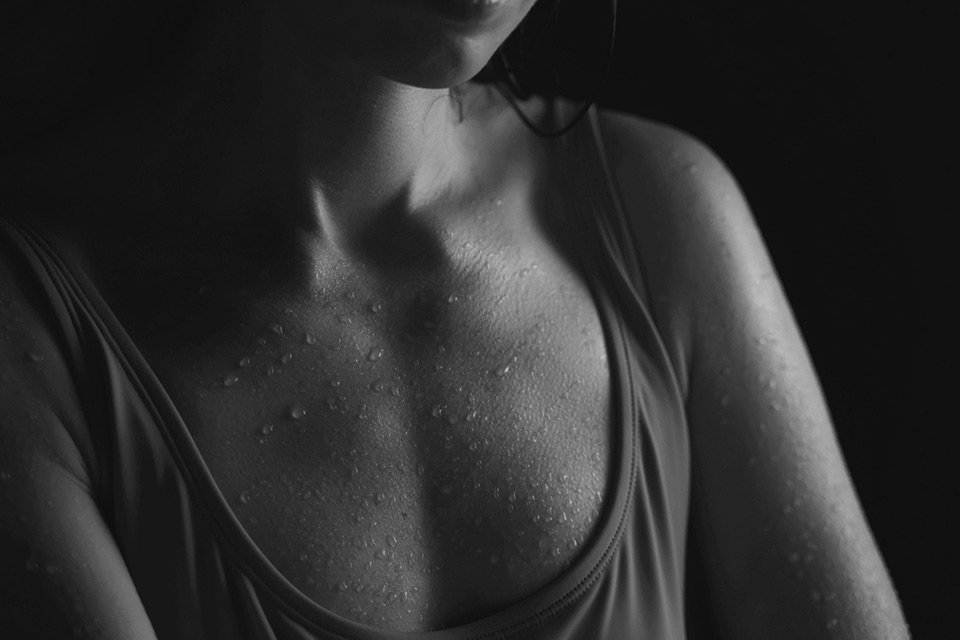 Black and white image of woman's torso with moisture on her skin