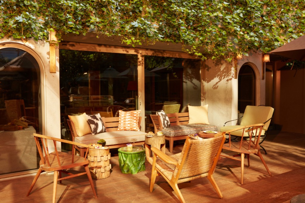 outdoor patio with greenery, chairs, and large windows
