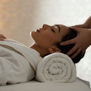 Woman laying down on a towel receiving a head massage