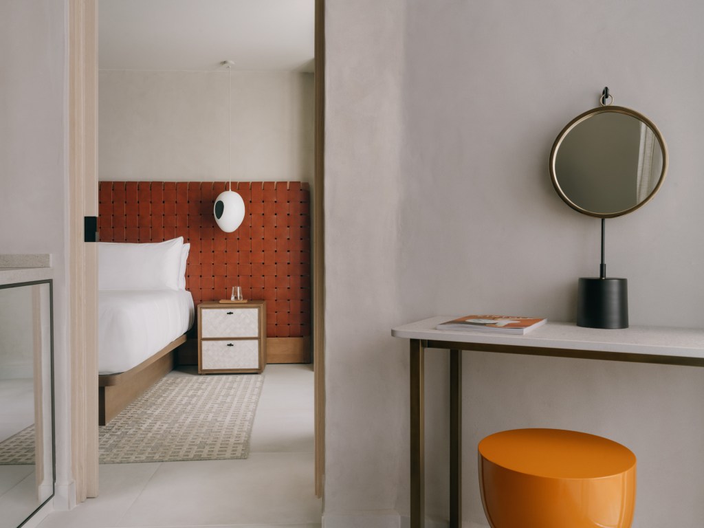 Good Mondrian Ibiza One Bedroom Suite Sea View, Hotel bedroom view through a door with a white bed, small bedside table, pendant white lamp, and rust colored headboard