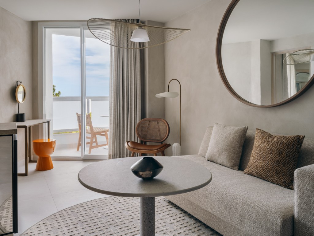 Good Mondrian Ibiza One Bedroom Suite Sea View, Suite living area with small round table, cream sofa, cream area rug, and a balcony in the background