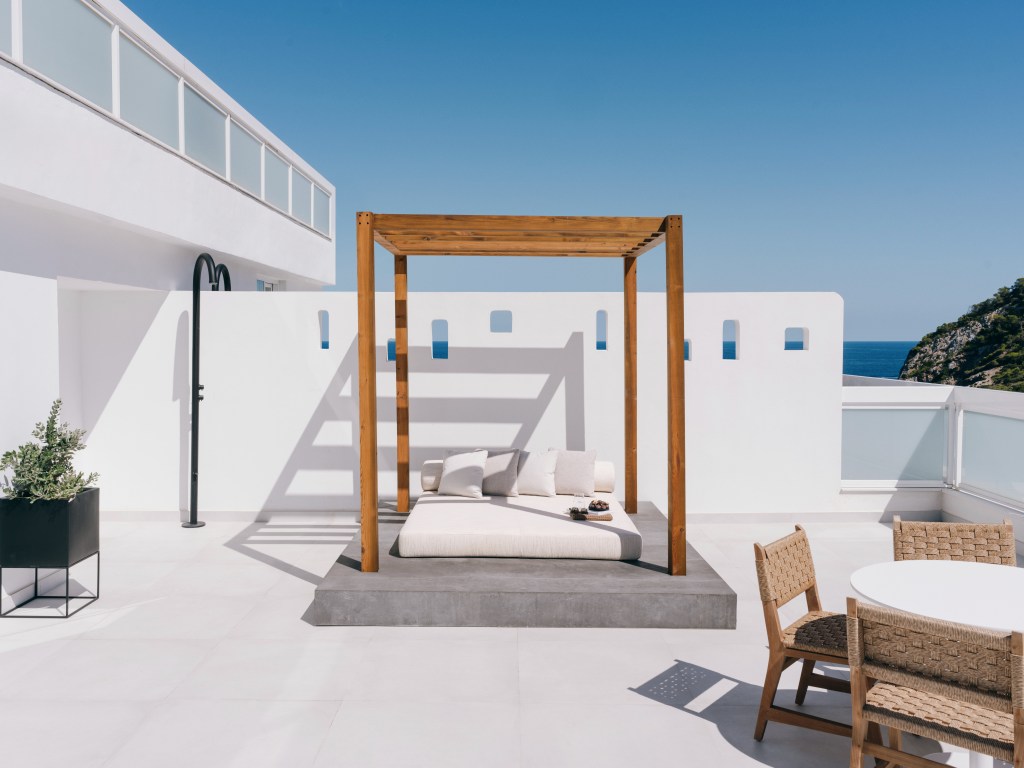 Good - White patio with wooden daybed and table.