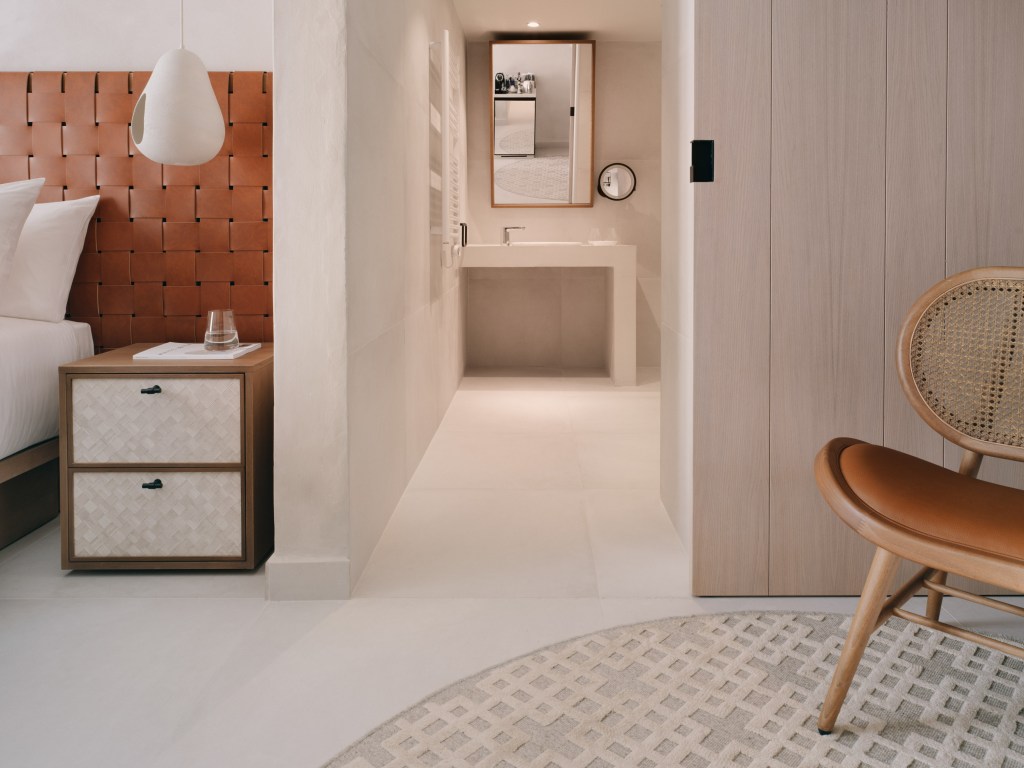 Mondrian Ibiza Hotel Deluxe King Accessible room with side table, rust colored headboard, and bathroom sink and mirror in the background with wheelchair facilities