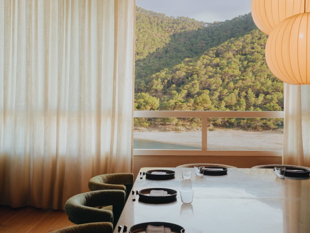 Niko Ibiza, japanese restaurant with sea views. Room with a rectangle table, plates and chairs.