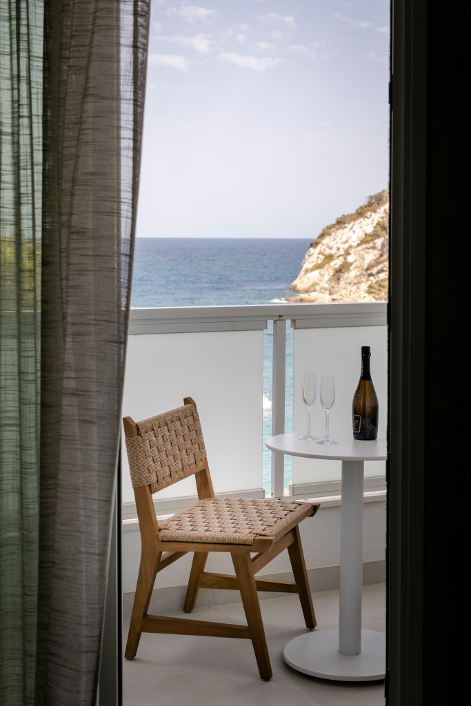 Mondrian Ibiza Deluxe King Sea View Room, balcony with a chair, table and seating area looking to the Mediterranean Sea