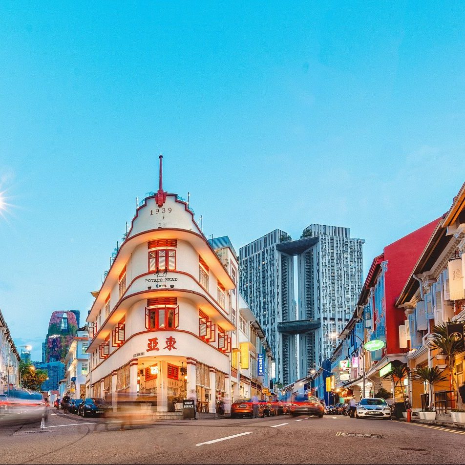 a view of Chinatown streets lit up with lights beneath a blue dim sky in the evening