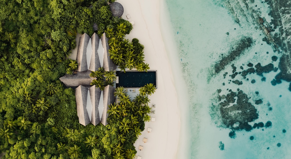 Aerial view of a resort on a beach with a large pool and turquoise ocean water