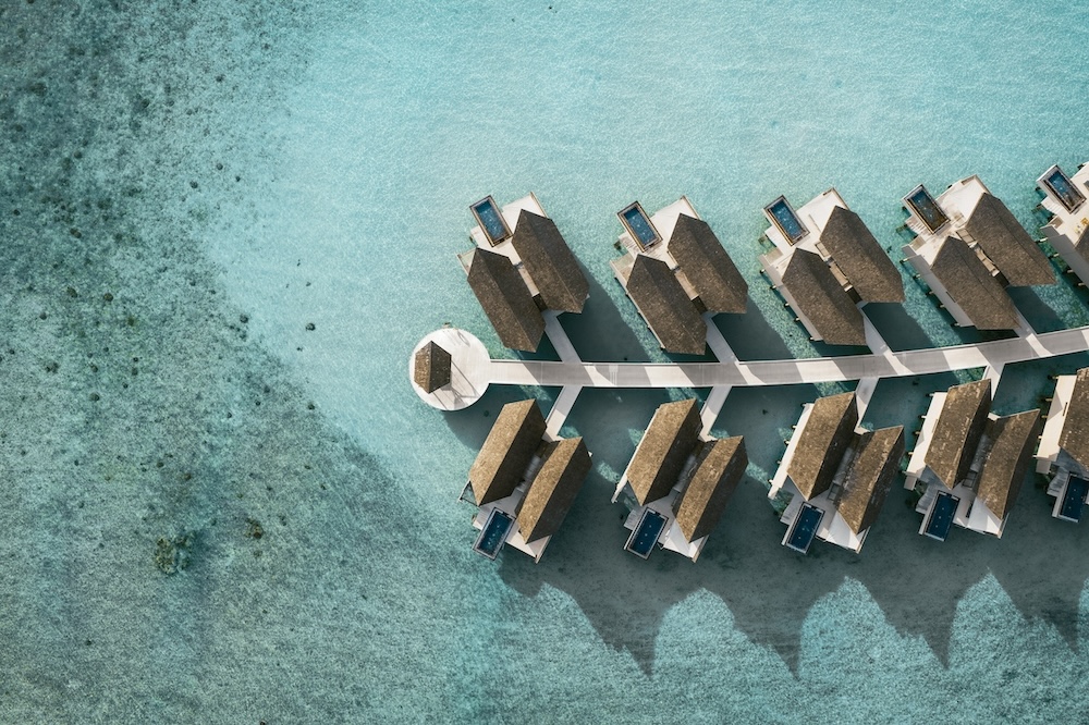 Aerial view of rows of ocean floating villas on turquoise ocean water