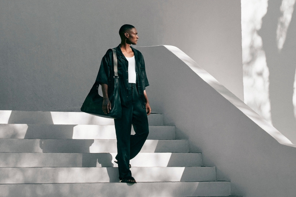 man in black top and pants walks down a set of concrete stairs