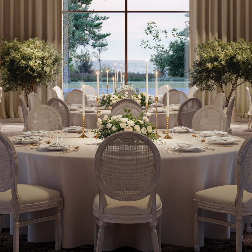 Large white table with white event chairs and flowers and candles on top