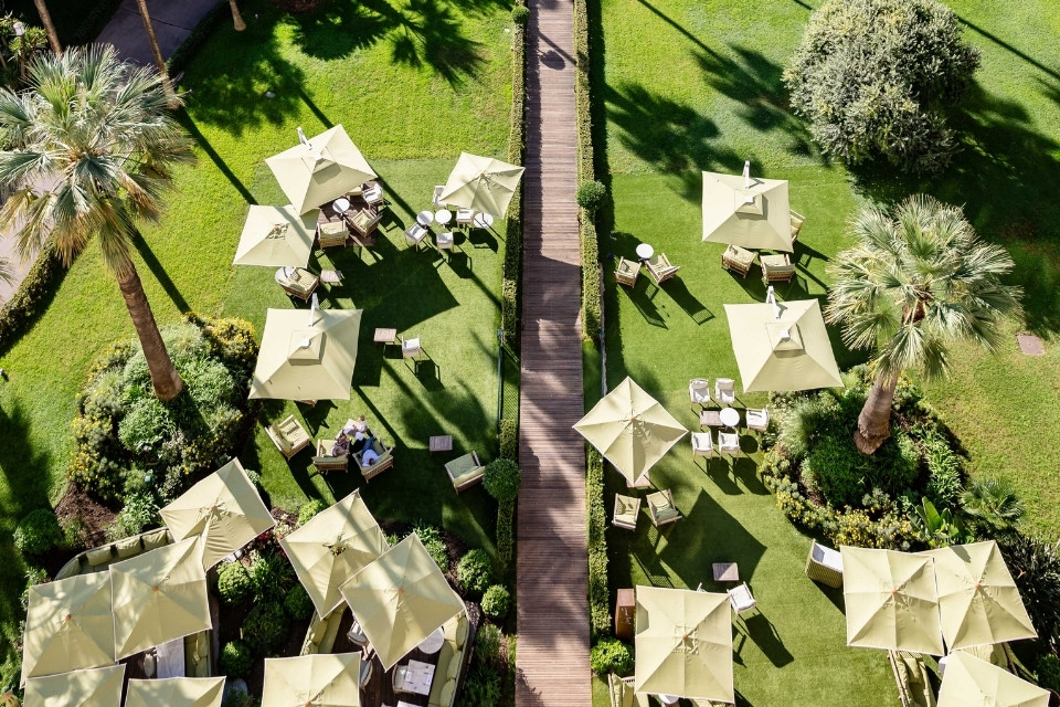 Overhead view of green garden with palm trees and green umbrellas