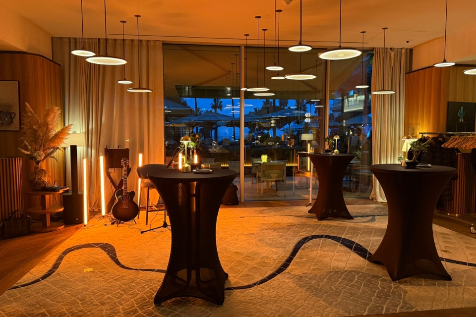 High tables with black tablecloths in a dimly lit restaurant space at night