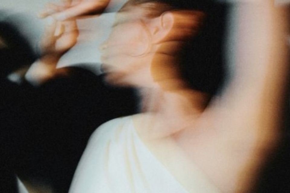 Blurred image of a woman in a white dress dancing