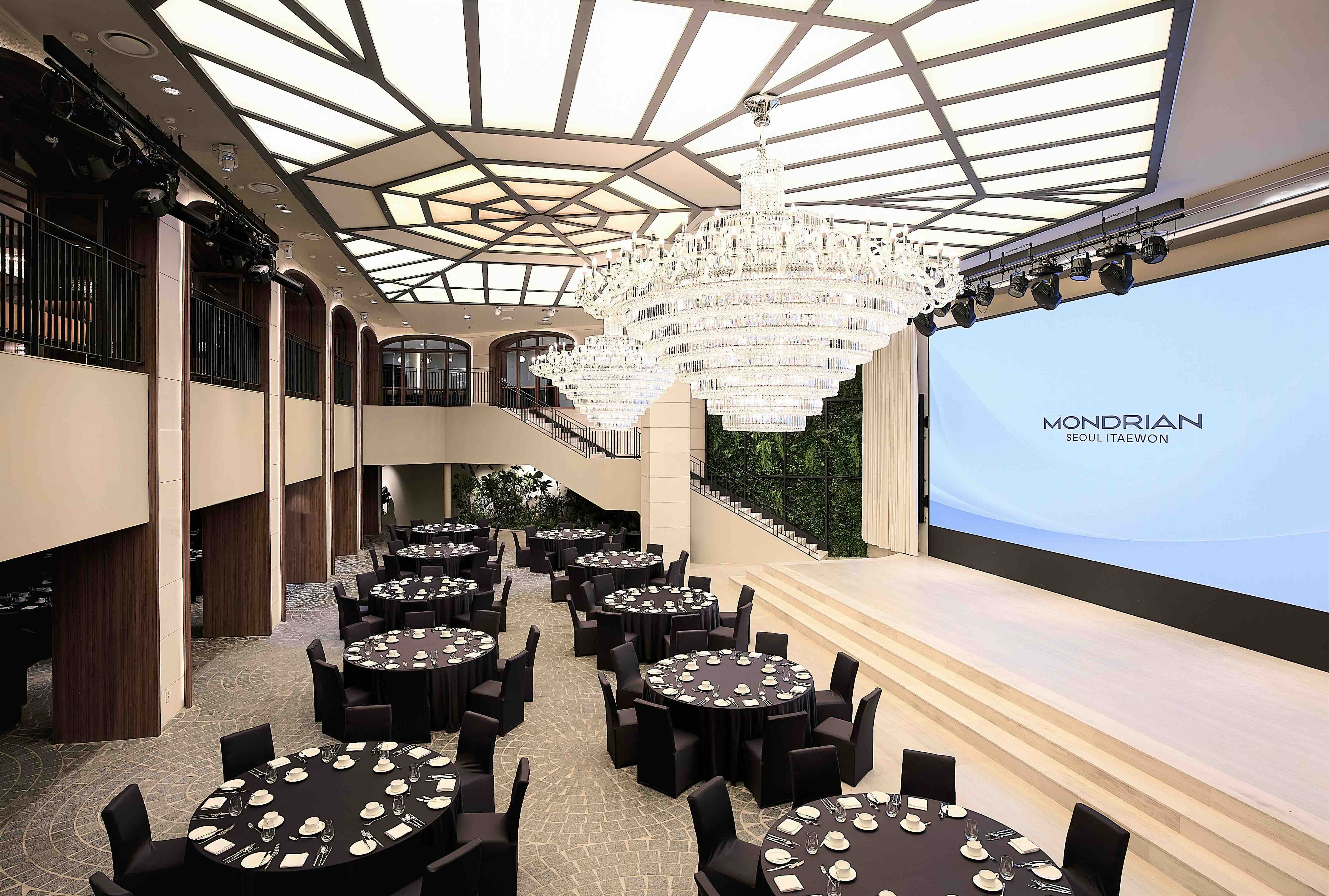 Large garden hall with round circle tables, a grand chandelier, and large projector screen