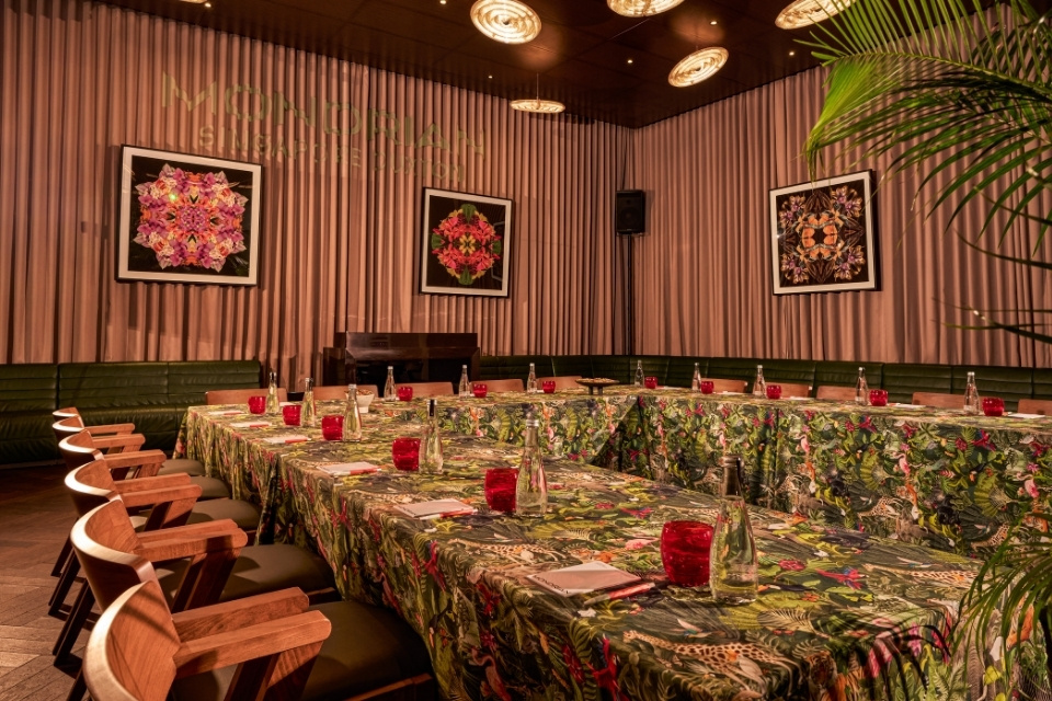 Large table with palm tree printed tablecloth and pink seats and bright decor throughout