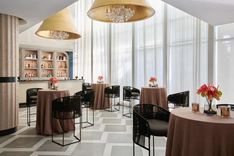 Ballroom space with grey carpet, brown hightop tables, and black chairs