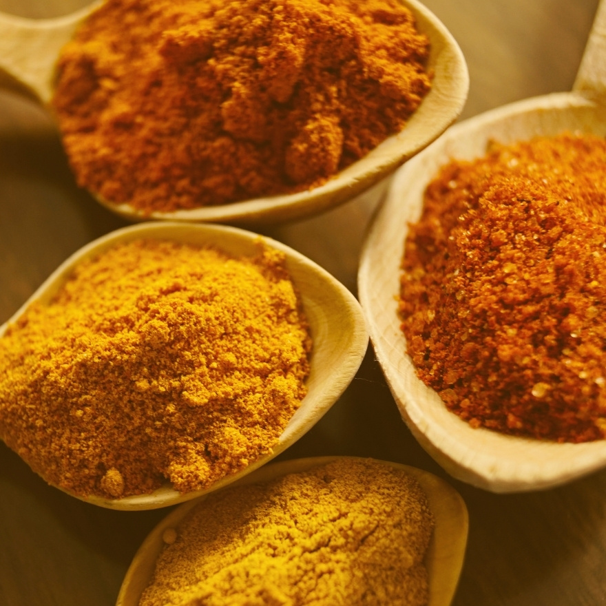 Yellow and orange spices on wooden spoons