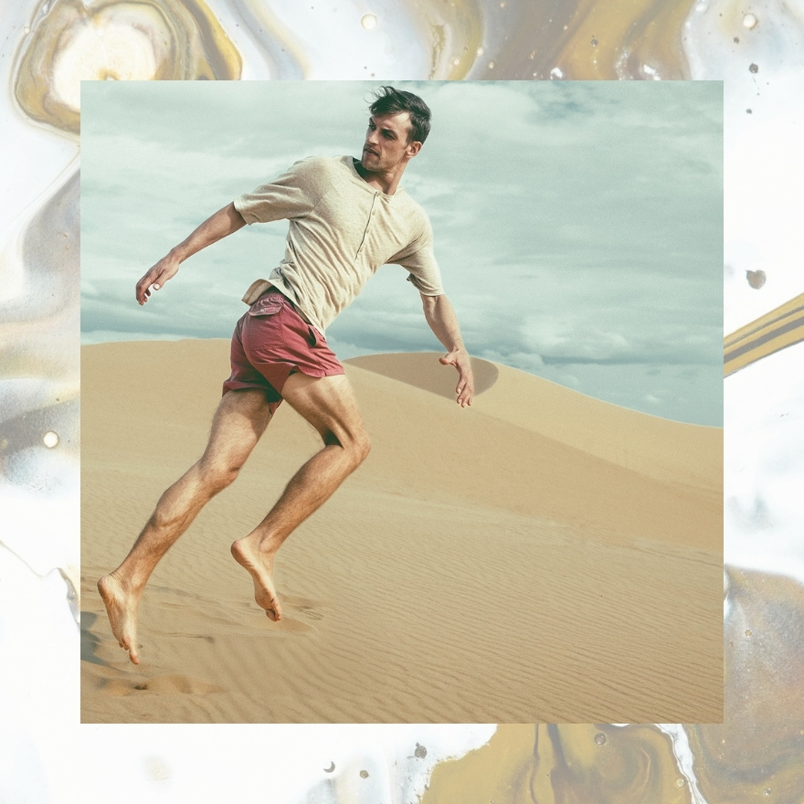 Man running on beach in red shorts and cream top