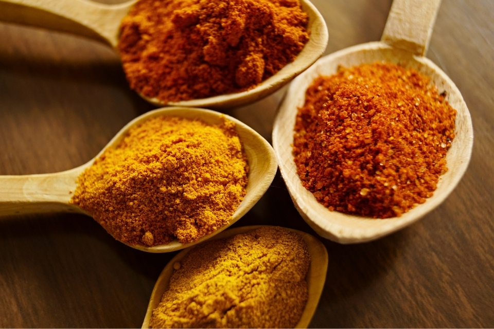 Orange and yellow spices on wooden spoons