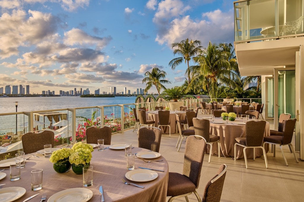 Outdoor event set up with round tables, chairs, and palm trees