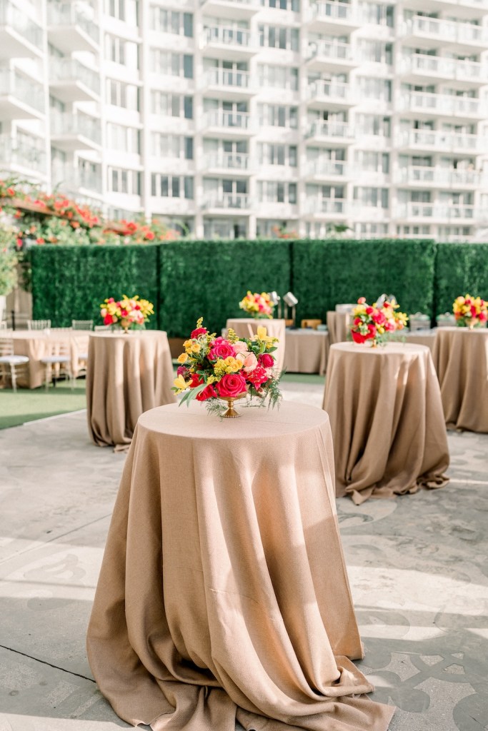 Light beige high top tables with colorful bouquets on an outdoor patio