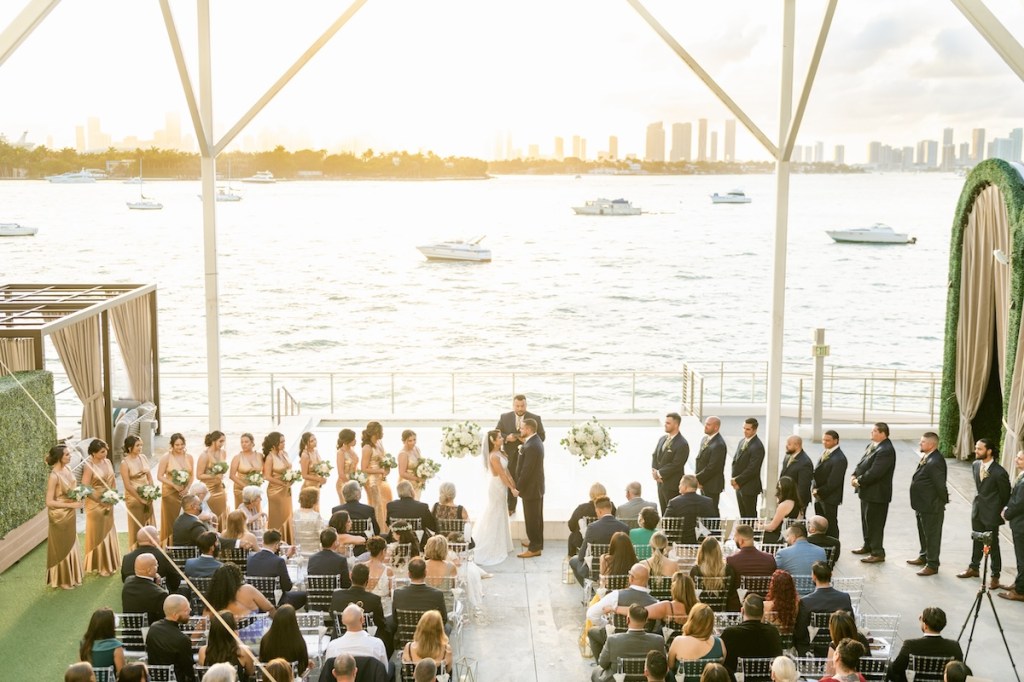 Large wedding party standing on a patio space overlooking the ocean