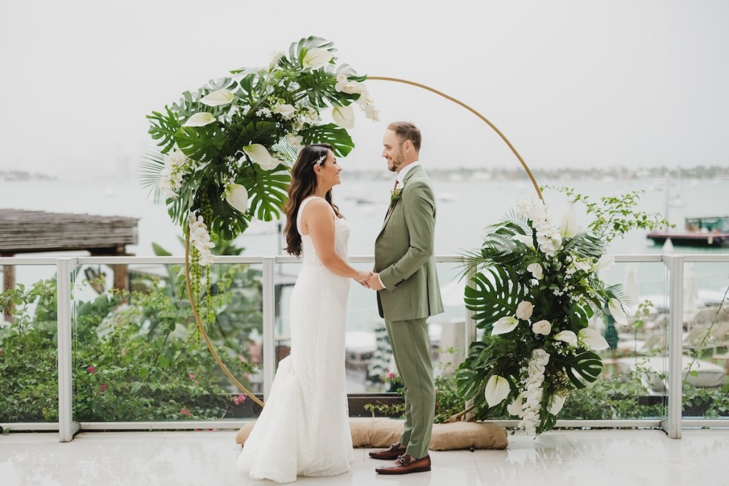 Bride and groom standing in front of floral altar outside