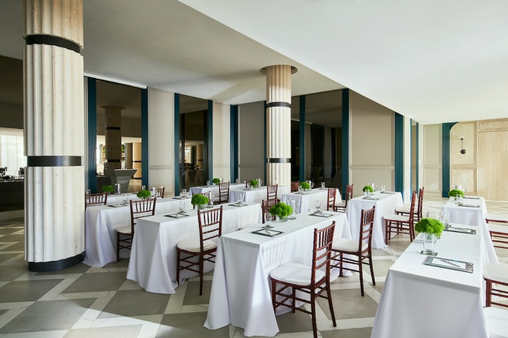 White rectangular tables set up in rows in a large ballroom space