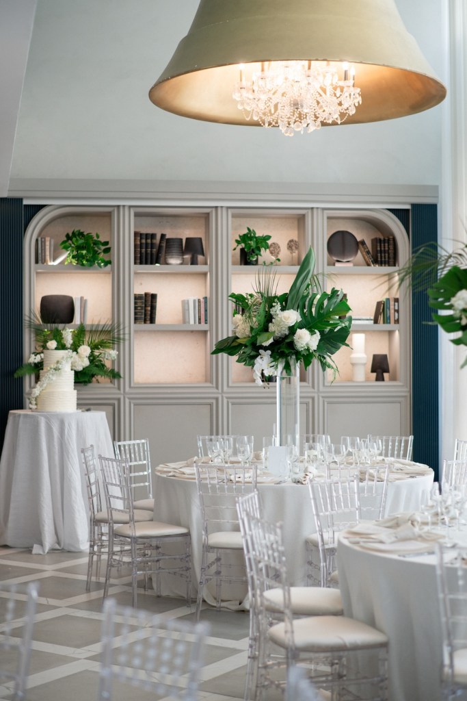 Ballroom with round white tables, chairs, and floral centerpieces
