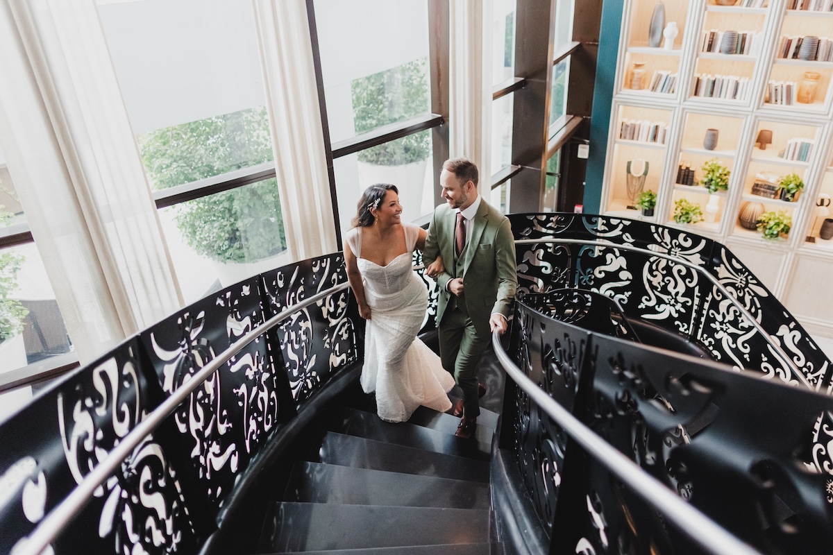Bride and groom walking up a black spiral staircase