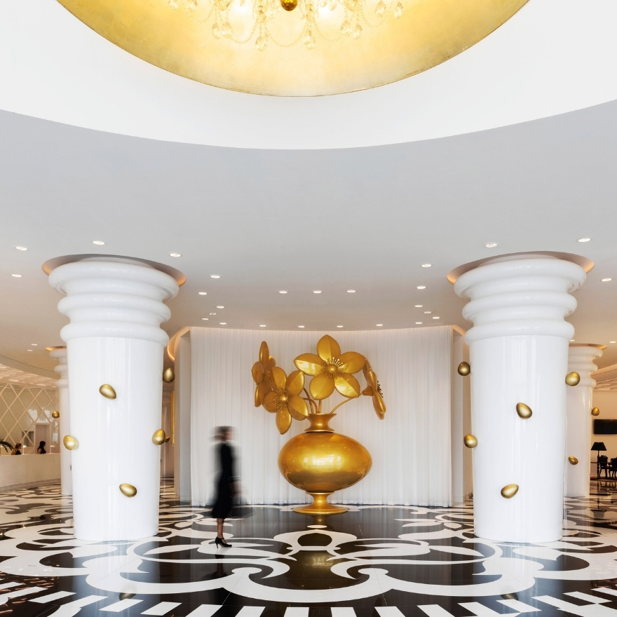 Large lobby with black and white floor and large white columns with large statue in the middle