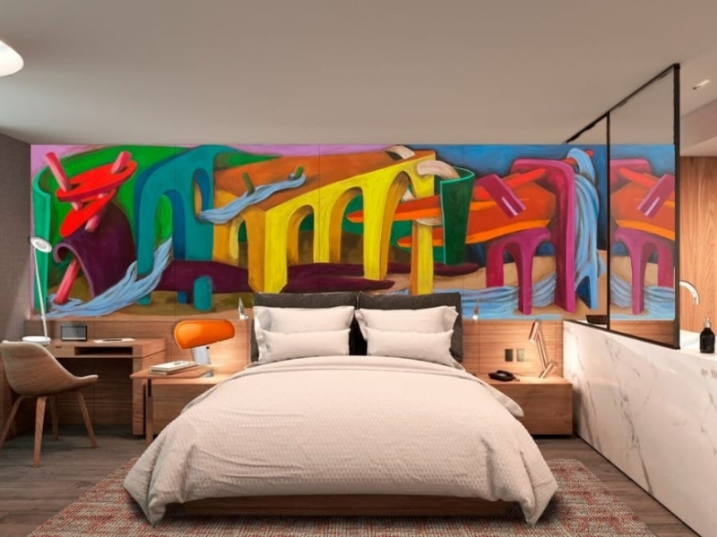 large white bed with colorful mural behind it