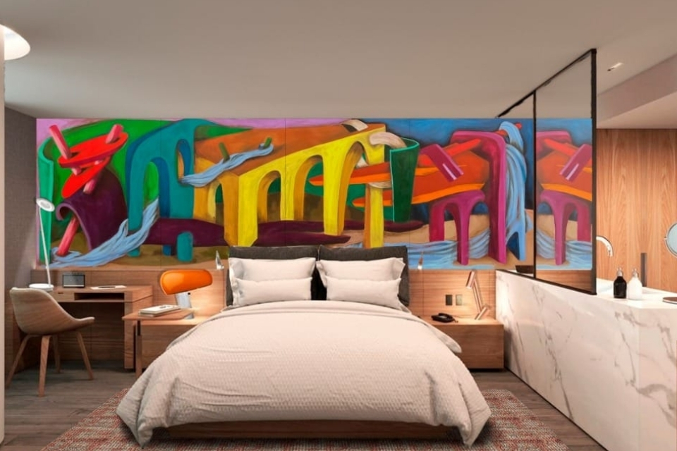 Large white bed with colorful mural behind it