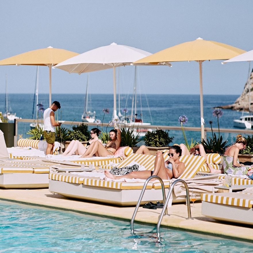 Chaises longues rayées avec parasols jaunes au bord d'une piscine